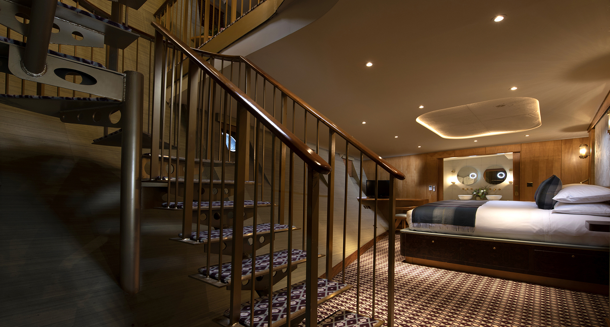 Luxury duplex suite bedroom aboard Fingal hotel Edinburgh, featuring spiral staircase, bespoke wood interiors, patterned flooring, and a beautifully appointed king-size bed.