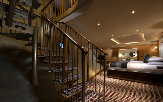 Luxury duplex suite bedroom aboard Fingal hotel Edinburgh, featuring spiral staircase, bespoke wood interiors, patterned flooring, and a beautifully appointed king-size bed.