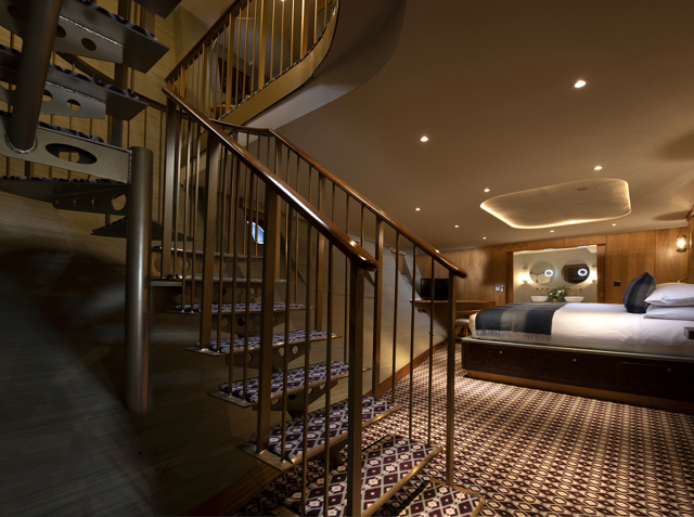 Luxury duplex suite bedroom aboard Fingal hotel Edinburgh, featuring spiral staircase, bespoke wood interiors, patterned flooring, and a beautifully appointed king-size bed.