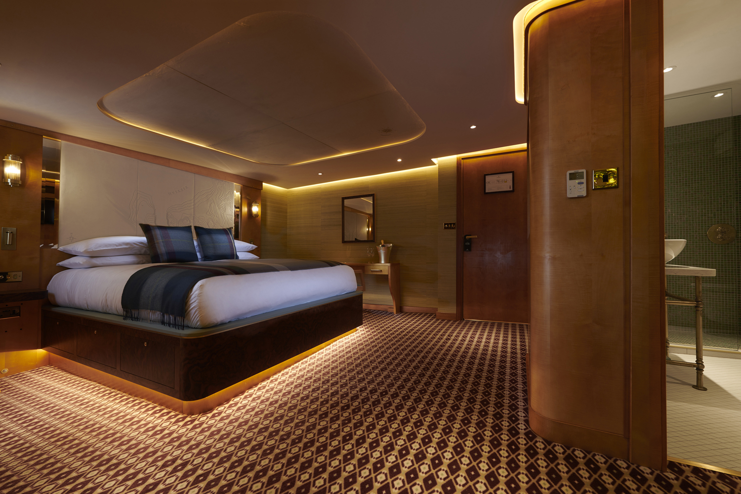 Image of a luxurious cabin with the bed neatly made and a warm dark atmosphere. 