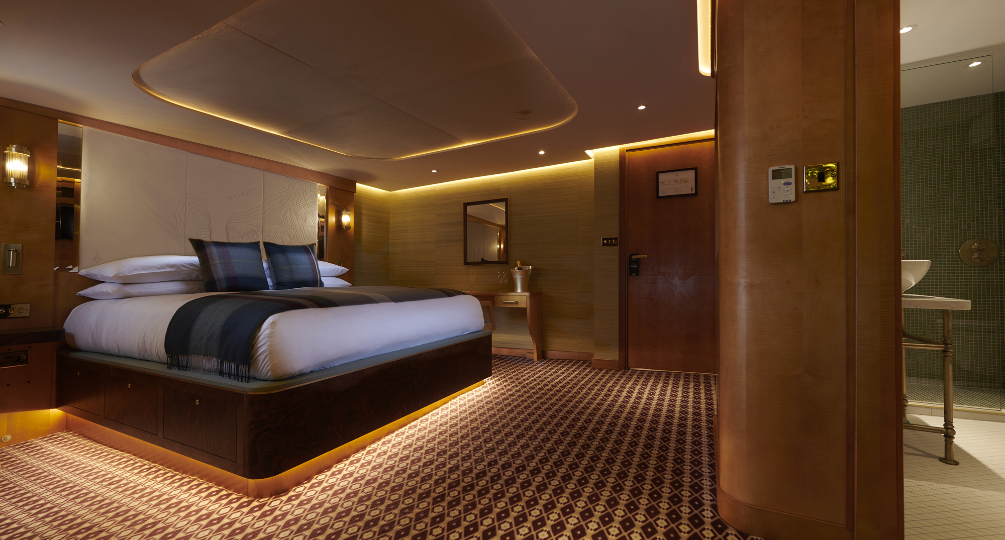 Image of a luxurious cabin with the bed neatly made and a warm dark atmosphere. 