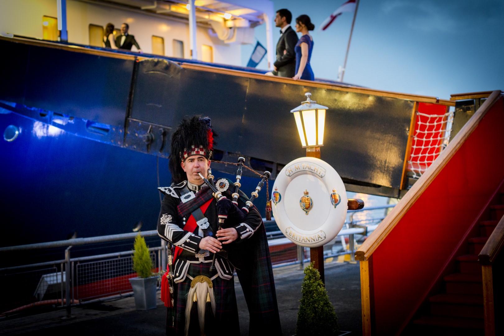 A piper is playing in front of the Royal Brow at The Royal Yacht Britannia. 