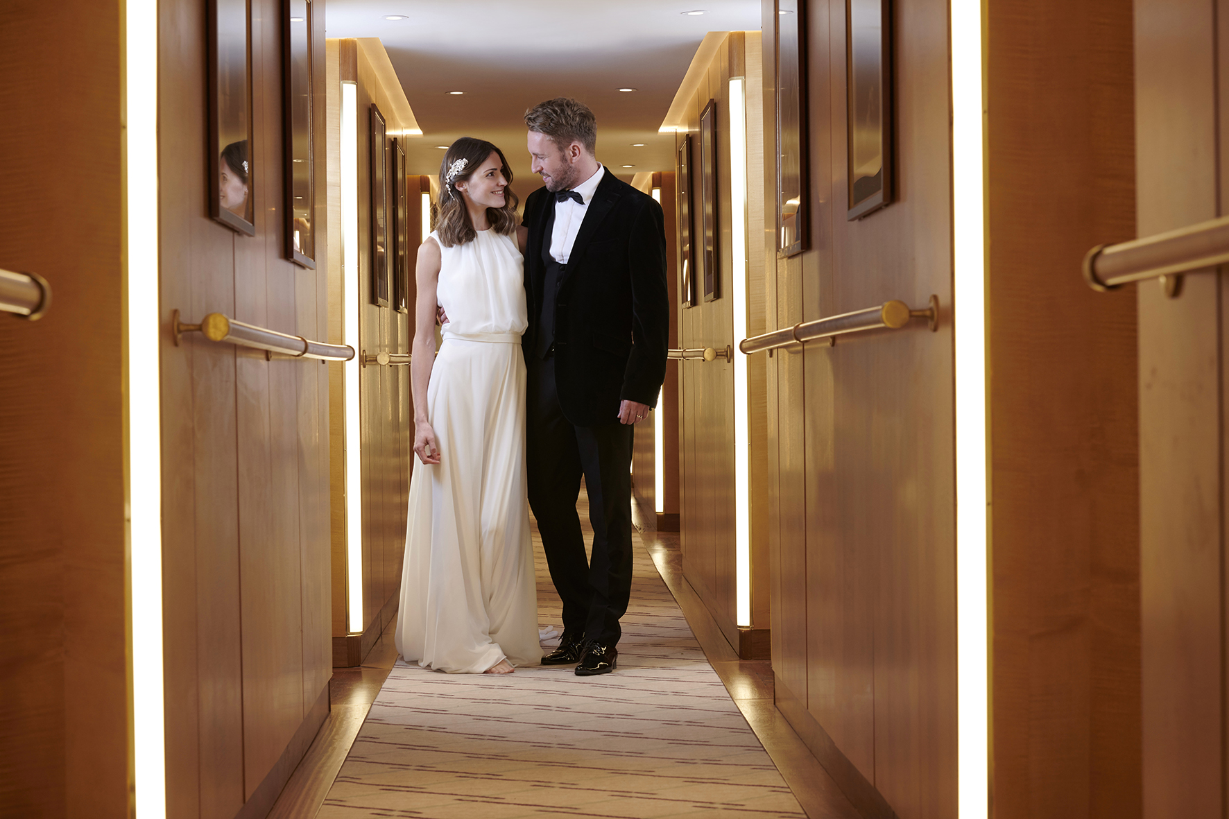 Bride and groom walking through the elegant hallway aboard Fingal Hotel in Edinburgh, representing a luxurious wedding or special occasion gift voucher experience.
