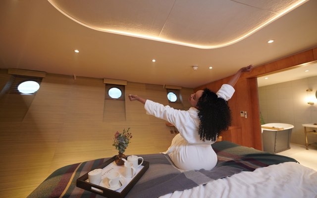 Girl stretches, getting out of bed, with both arms in the air