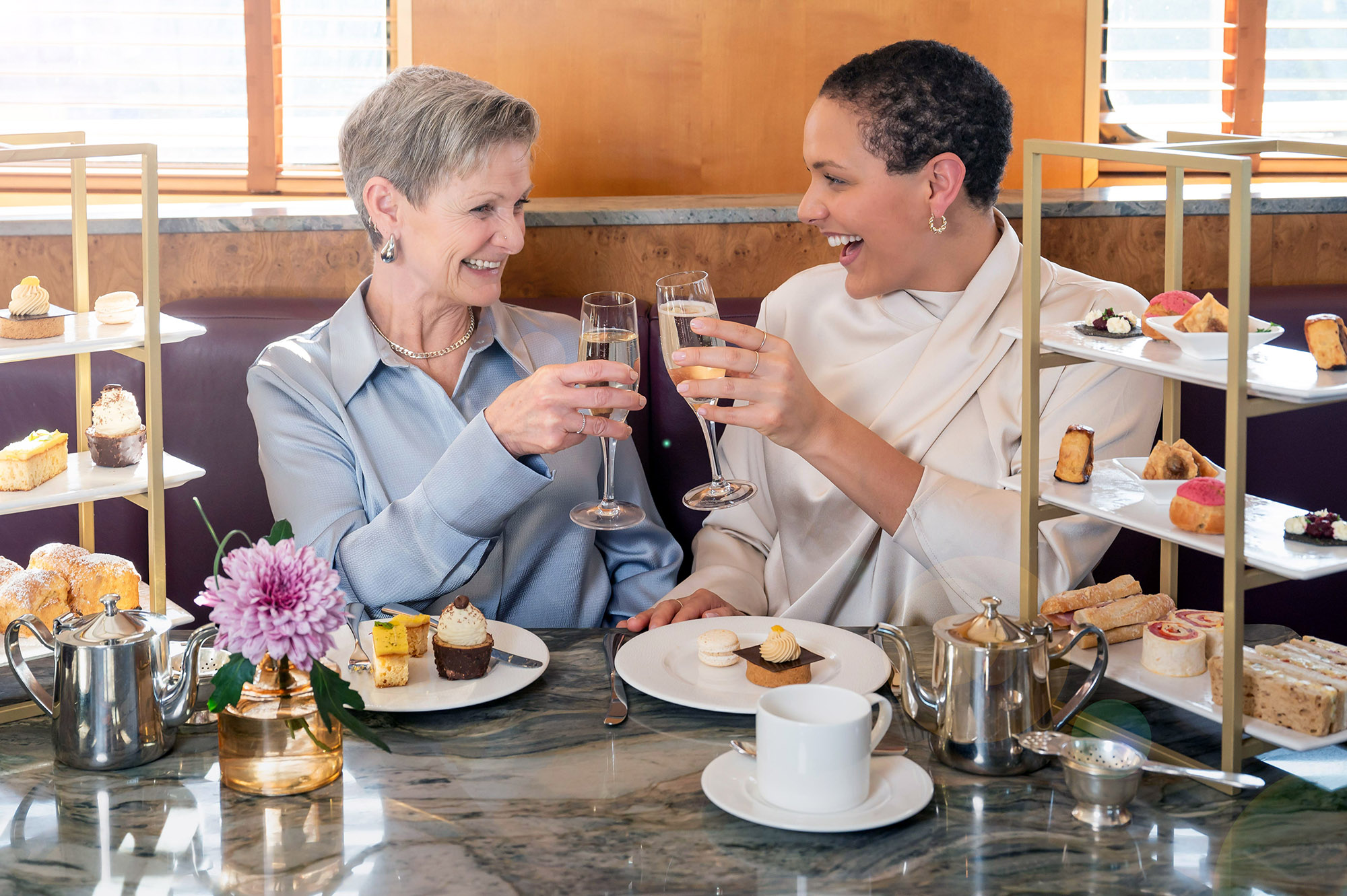 Mother and daughter enjoy Afternoon Tea as they toast each other with a glass of Champagne