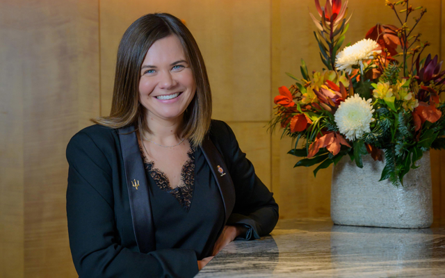 A woman is standing smiling at a bar in Fingal Hotel's Ballroom. 