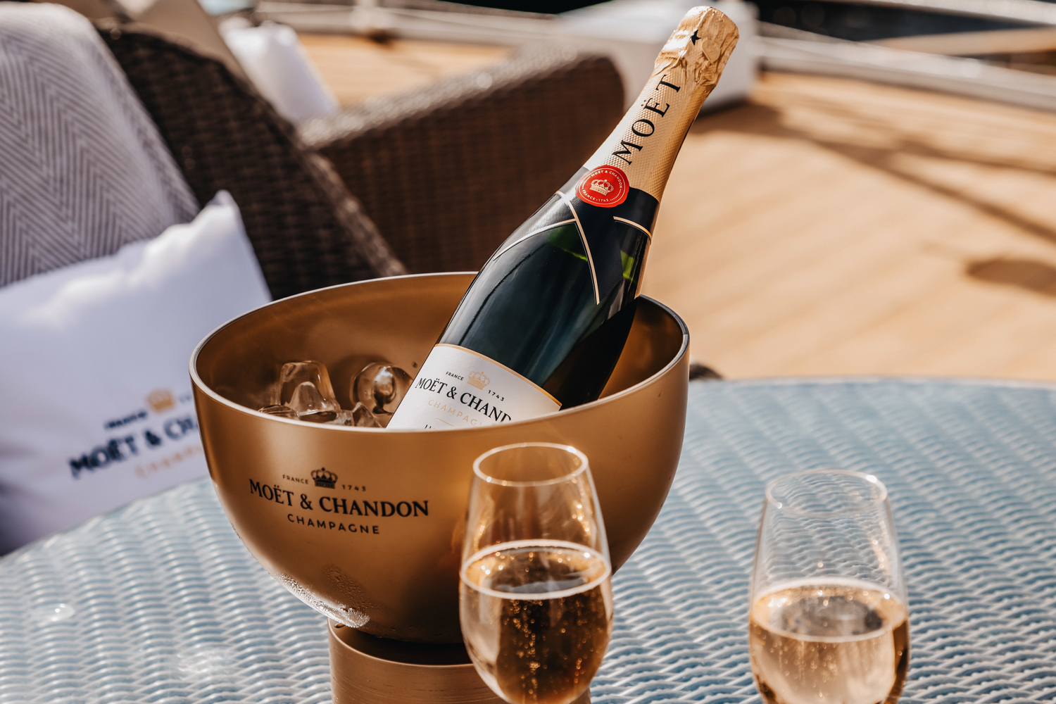 Two glasses and a bottle of Champagne which sits in a golden bucket of ice