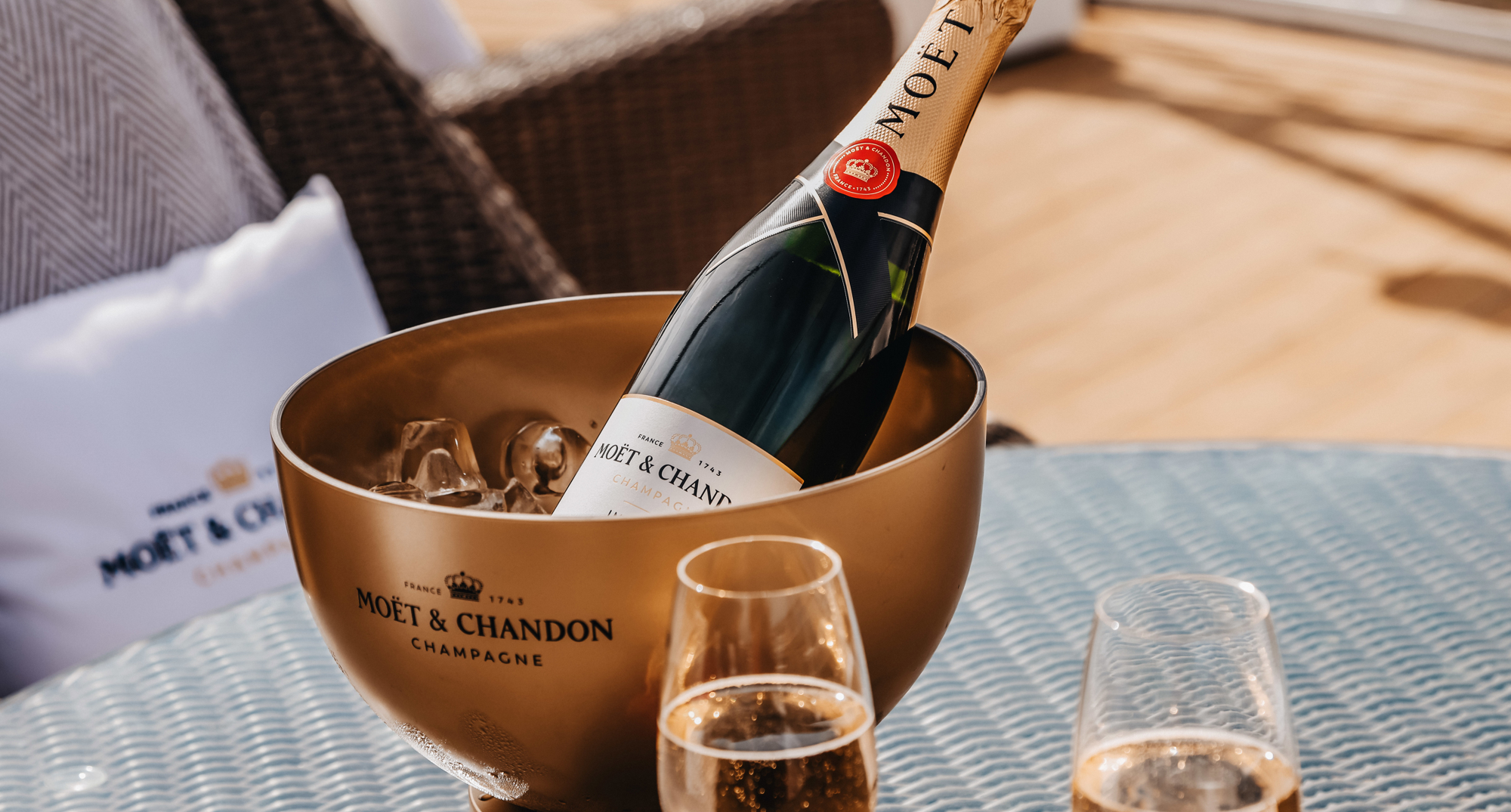 Two glasses and a bottle of Champagne which sits in a golden bucket of ice