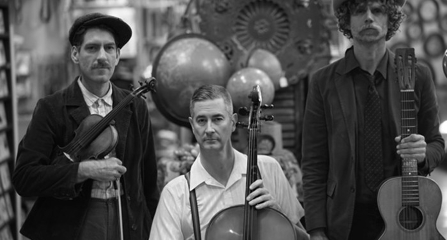Three men with stringed musical instruments including a violin, a bow cello and a guitar. 