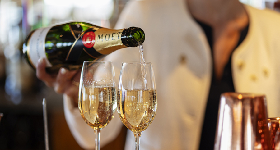 A woman is pouring a glass of Champagne in Fingal Hotel's Lighthouse Restaurant. 